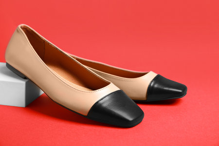 Pair of new stylish square toe ballet flats on red backgroundの写真素材