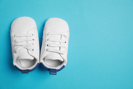 Cute baby shoes on light blue background, flat lay. Space for textの写真素材
