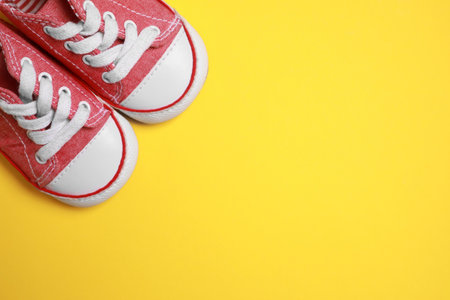 Cute baby shoes on yellow background, flat lay. Space for textの写真素材