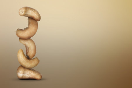 Stacked cashew nuts on light brown gradient background, space for textの写真素材