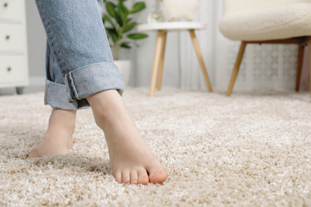 Woman standing on soft carpet at home, closeup. Space for textの写真素材