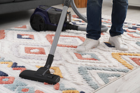 Man cleaning carpet with vacuum cleaner at home, closeupの写真素材