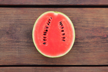 Half of delicious ripe watermelon on wooden table, top viewの写真素材