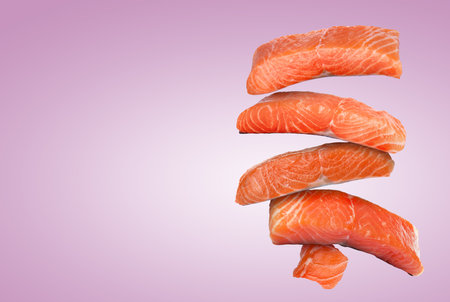 Cut fresh salmon falling on violet gradient background, space for textの写真素材