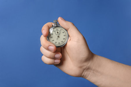 Man holding vintage timer on blue background, closeupの写真素材