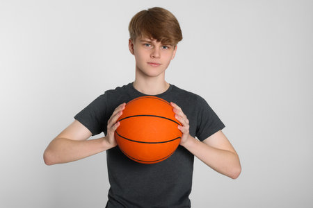 Teenage boy with basketball ball on light grey backgroundの写真素材