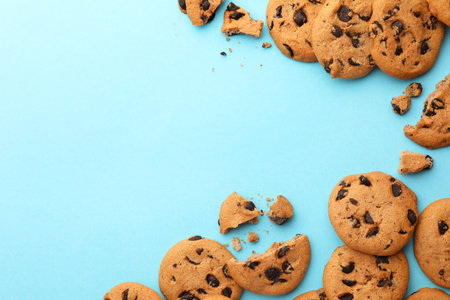 Many delicious chocolate chip cookies on light blue background, flat lay. Space for textの写真素材