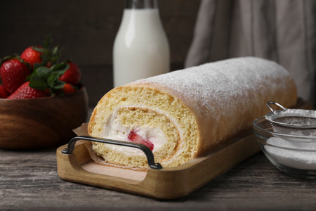 Delicious sponge cake roll with strawberries and cream on wooden tableの写真素材