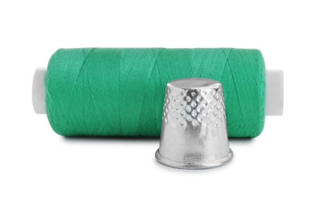 Thimble and spool of green sewing thread isolated on whiteの写真素材