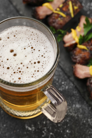 Mug with beer and delicious grilled ribs on dark gray textured tableの写真素材