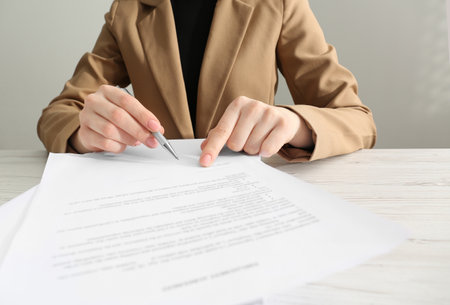 Woman signing document at wooden table, closeupの写真素材
