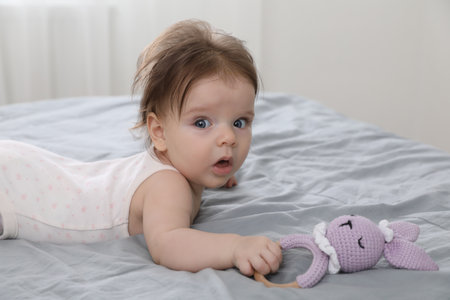Cute little baby with toy on bed indoors. Space for text