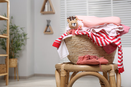 Laundry basket with baby clothes and crochet toy indoors, space for textの写真素材