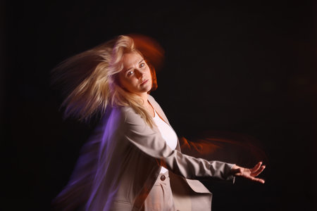 Young woman performing contemporary dance on black background, motion blur effectの写真素材