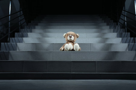 Lonely teddy bear on gray stairs indoors, low angle viewの写真素材