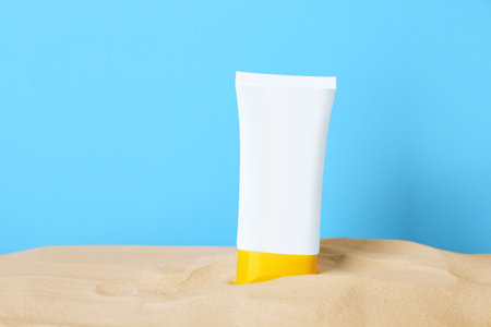 Suntan product in sand against light blue background. Space for textの写真素材