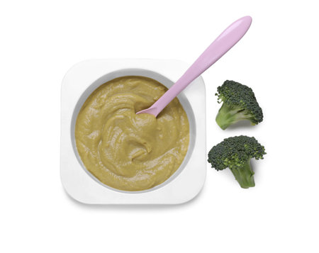 Container with healthy baby food, spoon and broccoli isolated on white, top viewの写真素材