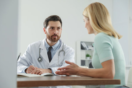 Doctor consulting patient at wooden table in clinicの写真素材