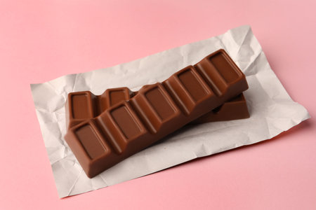 Paper wrap with delicious chocolate bars on pink backgroundの写真素材