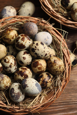 Wicker bowl with quail eggs and straw on wooden table, flat layの写真素材