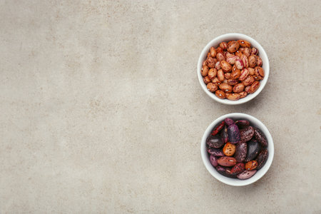 Bowls with different types of beans on light gray table, flat lay. Space for text
