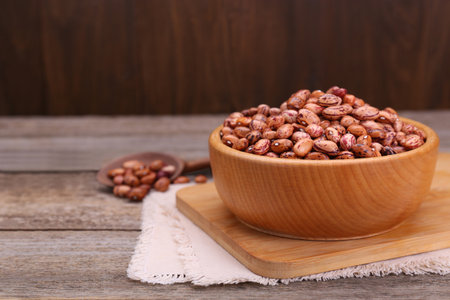Bowl with dry kidney beans on old wooden table, closeup. Space for text
