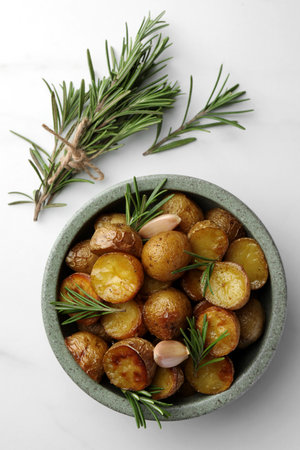 Tasty baked potato and aromatic rosemary on white marble table, flat layの写真素材