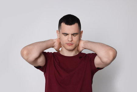 Man suffering from pain in his neck on light background. Arthritis symptomsの写真素材