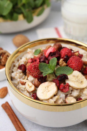 Delicious oatmeal with freeze dried berries, banana, nuts and mint on table, closeupの写真素材