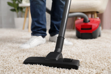 Man cleaning carpet with vacuum cleaner at home, closeupの写真素材