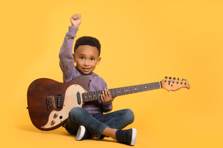 African-American boy with electric guitar on yellow background. Space for textの写真素材