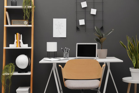 Cozy workplace with modern laptop on desk and comfortable chair at homeの写真素材