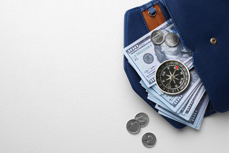 Exchange rate. Wallet with money (dollar banknotes and coins) and compass on white background, top view. Space for textの写真素材