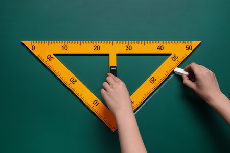 Woman drawing with chalk and triangle ruler on green board, closeupの写真素材