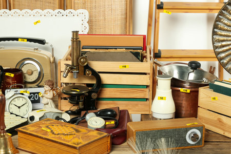 Many different items on wooden table indoors. Garage sale