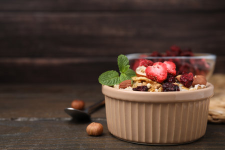 Oatmeal with freeze dried fruits, nuts and mint on wooden table, closeup. Space for textの写真素材