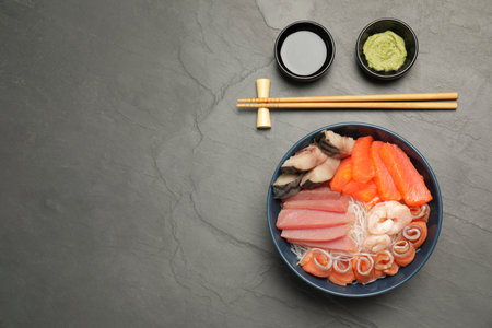 Delicious mackerel, salmon, shrimps and tuna served with funchosa, wasabi and soy sauce on gray table, flat lay with space for text. Tasty sashimi dishの写真素材
