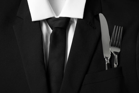 Man's jacket with cutlery as background, closeup. Business lunch conceptの写真素材