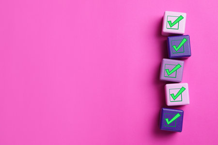 Cubes with check marks on pink background, flat lay. Space for textの写真素材