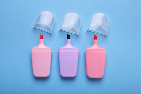 Colorful markers with caps on light blue background, flat lay