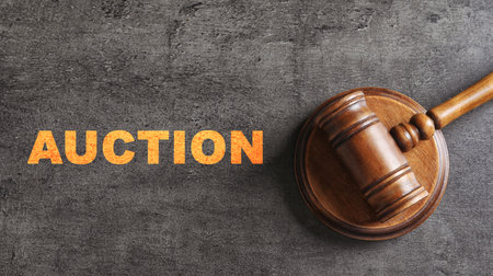 Word Auction and wooden gavel on gray textured table, top view