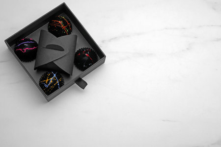 Box of tasty chocolate candies on white table, top view. Space for text