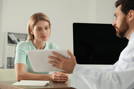 Doctor consulting patient at wooden table in clinicの写真素材