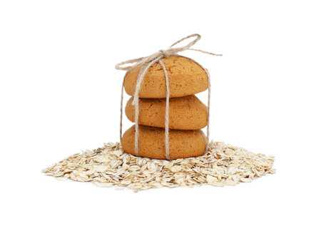 Delicious oatmeal cookies tied with twine and flakes on white backgroundの写真素材