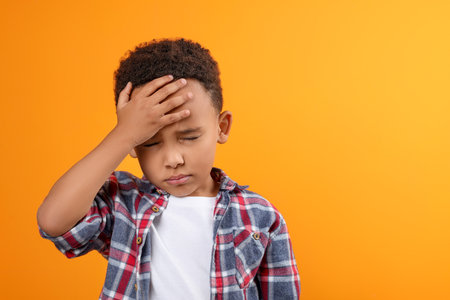 Portrait of emotional African-American boy on orange background. Space for textの写真素材