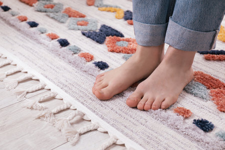 Woman standing on carpet with pattern at home, closeupの写真素材