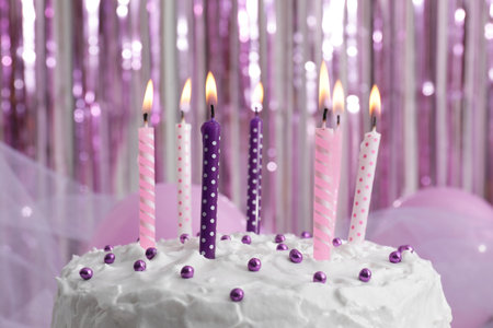 Delicious cake with cream and burning candles on color background, closeupの写真素材
