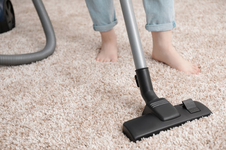 Woman cleaning carpet with vacuum cleaner, closeup. Space for textの写真素材