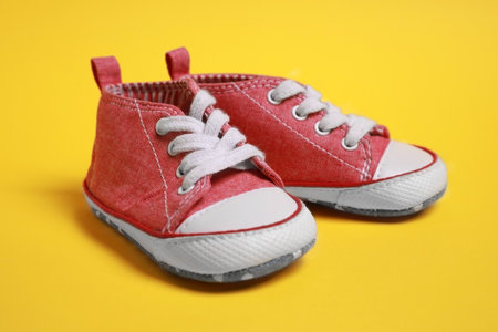 Pair of cute baby shoes on yellow background, closeupの写真素材