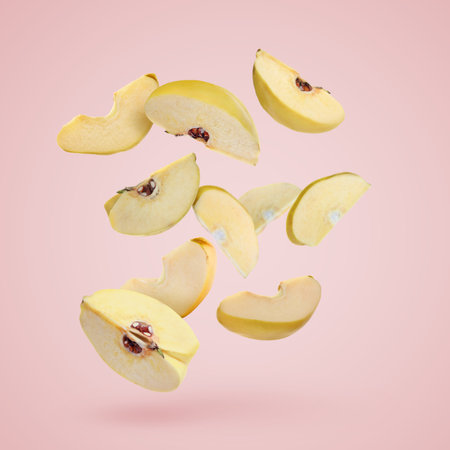 Quince pieces falling on pastel pink backgroundの写真素材